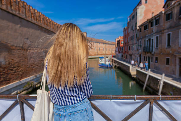 istock Blond woman standing on the bridge above canal 1396244311