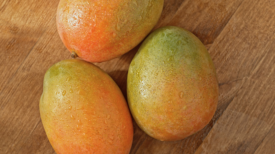 Close-up of mango fruits with water drop on wooden table.
