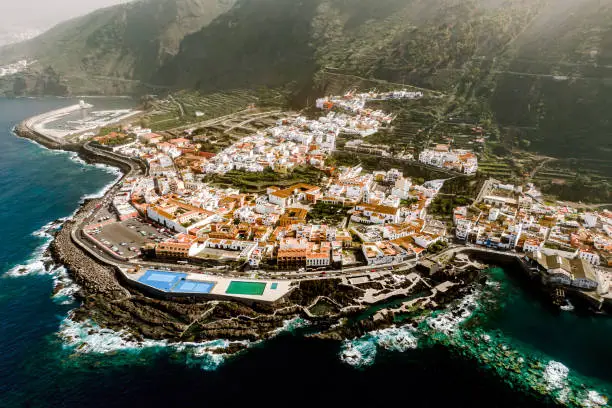 Photo of Aerial view of Garachico village on the coast of the Atlantic ocean in Tenerife island of Spain. Town on a rocky shore under the volcano mountain.