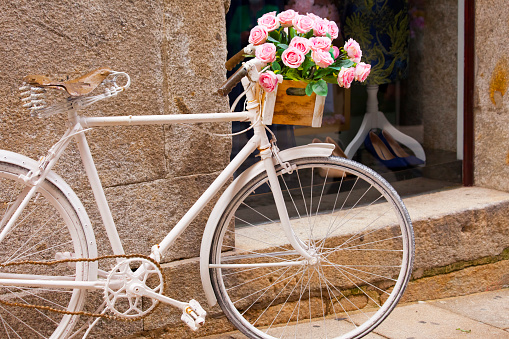 Old bicycle leaning in the street, decoration purposes,  crate with beautiful rose flower bunch. Valença de Minho, Portugal.