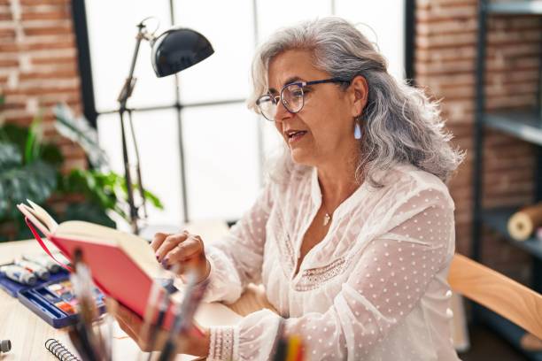 istock Middle age woman artist reading book at art studio 1396251024