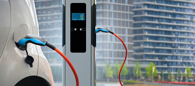 Close up of electric car with a charging station on the background of a modern building