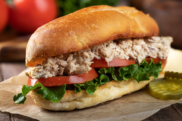 Tuna salad lettuce and tomato submarine sandwich Closeup of a tuna salad, lettuce and tomato submarine sandwich with pickles seafood salad stock pictures, royalty-free photos & images