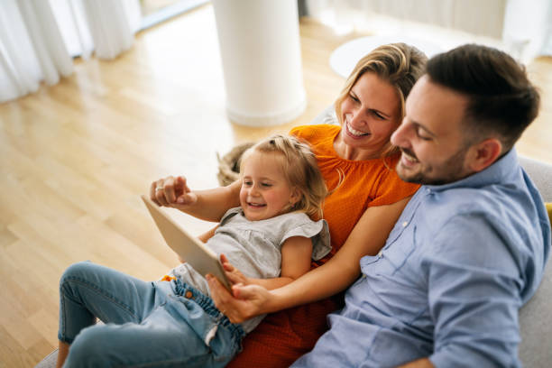 istock Happy young family having fun time at home. Parents with children using digital device. 1396256597