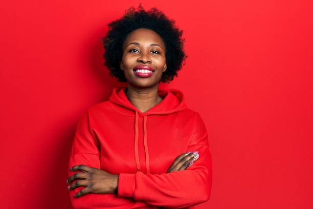 Young african american woman wearing casual sweatshirt happy face smiling with crossed arms looking at the camera. positive person. stock photo