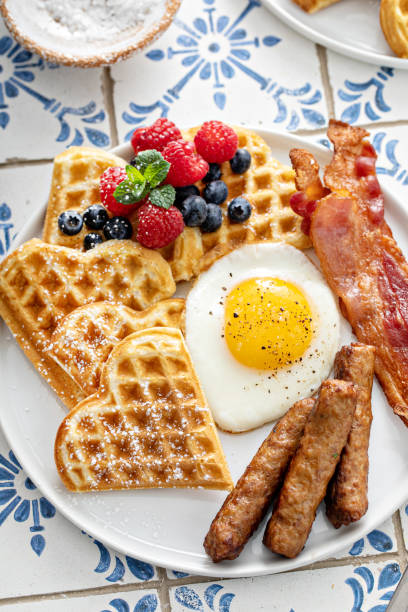 table de petit-déjeuner avec gaufres. œuf au plat, bacon et saucisse - waffle sausage breakfast food photos et images de collection