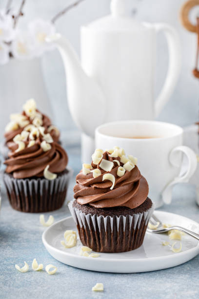 dunkle schokoladen-cupcakes mit geschlagenem ganache-frosting und weißen schokoladenlocken - cupcake chocolate icing candy stock-fotos und bilder