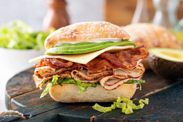 Fresh and healthy avocado turkey sandwich with swiss cheese Fresh and healthy avocado turkey sandwich with swiss cheese and bacon on chiabatta roll cooked bacon slice stock pictures, royalty-free photos & images