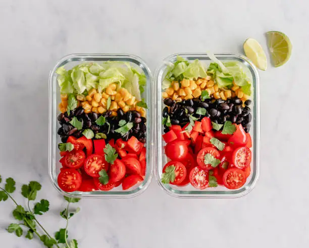 Overhead view of two glass meal prep containers with black bean salad