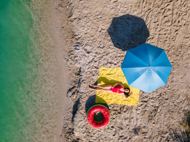 istock overhead view woman sunbathing at sandy beach 1396261403