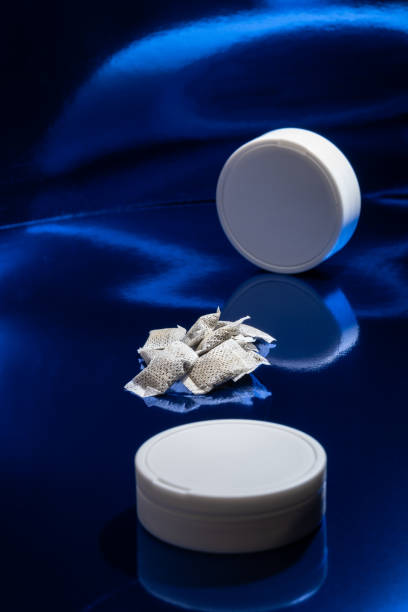 Closeup of white Swedish snus pouches against a blue background. Smokeless tobacco. stock photo