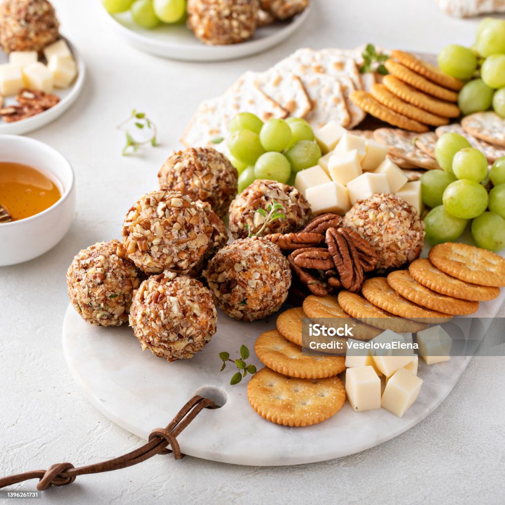 Cheese balls or truffles on a cheese board with crackers Cheese balls or truffles on a cheese board with crackers and grapes Cheese Ball Stock Photo