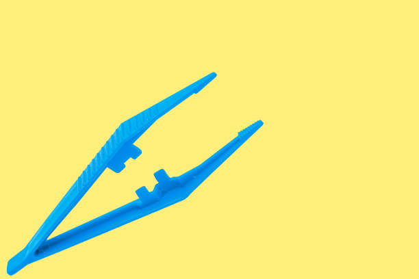 istock Tweezers isolated on yellow. 1396264053
