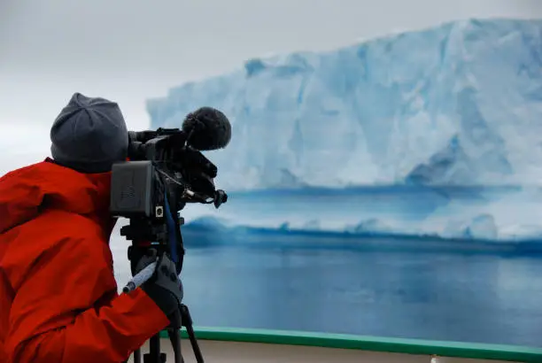 Photo of Cameraman filming an iceberg in Antarctica