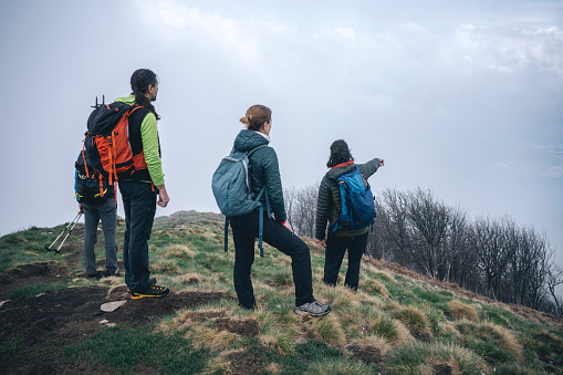 Group of hikers looking from mountain top at the cloudy panorama on the lake