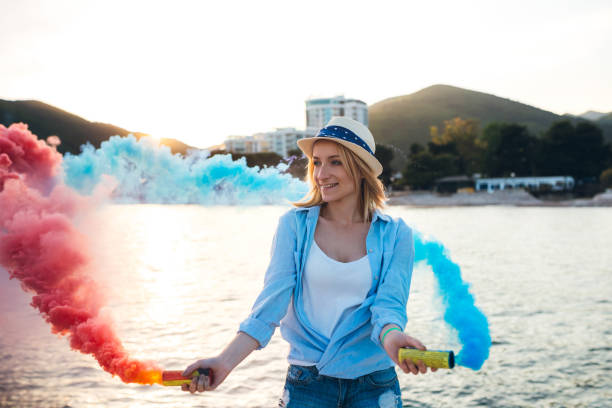 Young caucasian beautiful woman having fun with smoke bomb on the beach in Budva.