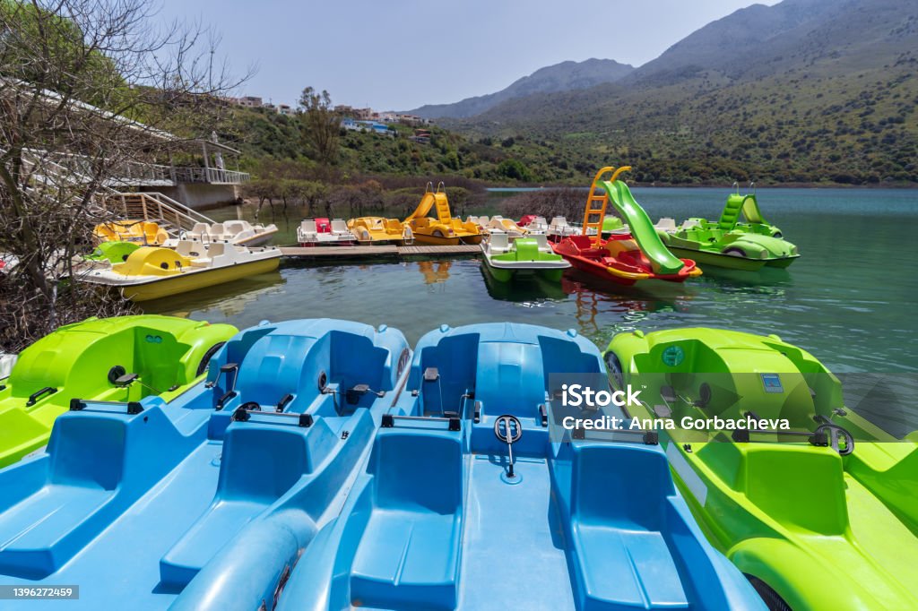 Pedal boats on the Lake Group of colorful pedal boats next to the wooden pier of Lake Kournas, Crete. Active rest outdoor Pedal Boat Stock Photo