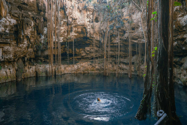 Young Caucasian man swimming in the centre of Cenote in Yucatan, Mexico