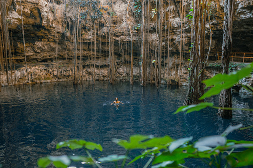Young Caucasian man swimming in the centre of Cenote in Yucatan, Mexico