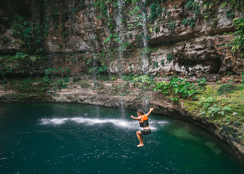 Young Caucasian man  jumping  into Cenote in Yucatan, Mexico