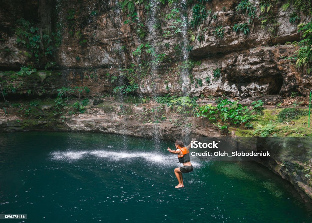 Man jumping  into Cenote in Yucatan, Mexico Young Caucasian man  jumping  into Cenote in Yucatan, Mexico Cenote Stock Photo