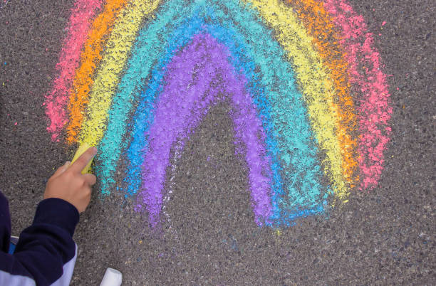 istock A child draws a rainbow on the asphalt. Selective focus. 1396278683