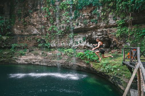 Young Caucasian man  jumping  into Cenote in Yucatan, Mexico