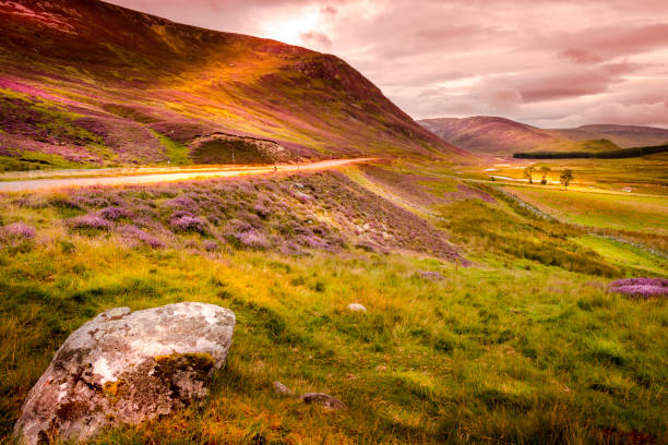 Braemar Mountain Sunset Beautiful Braemar Mountain Sunset beside road, hills with rock sitting on grass with shades of sun on mountains. cairngorm mountains stock pictures, royalty-free photos & images