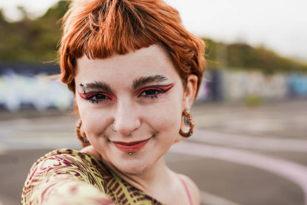 joven pelirroja loca sonriendo ante la cámara mientras se toma una selfie - bizarre women portrait pierced fotografías e imágenes de stock