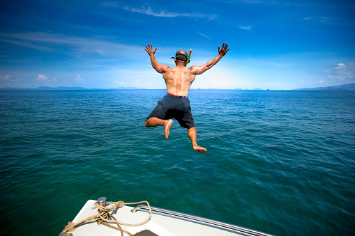 A man jumping from the boat to diving.