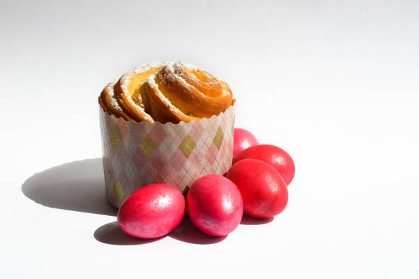 boiled red chicken eggs and cupcake with raisins and powdered sugar on a white background. preparation for the Easter holiday.