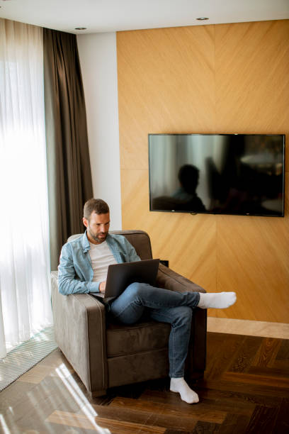 istock Young man using laptop in the living room 1396285505