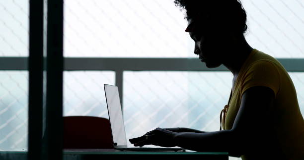 istock Silhouette young black woman typing on laptop computer at home 1396286578