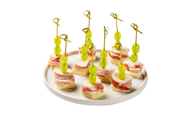 Delicious canapes with ham and grapes stock photo