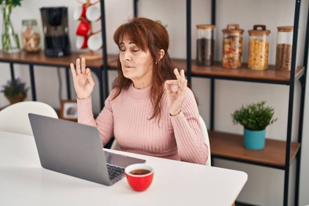 istock Middle age woman doing yoga exercise sitting on table at home 1396288431