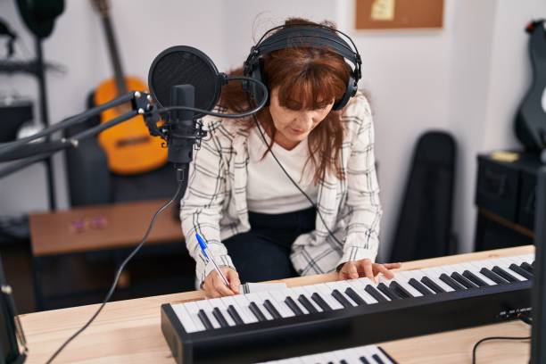 istock Middle age woman musician composing song at music studio 1396288432