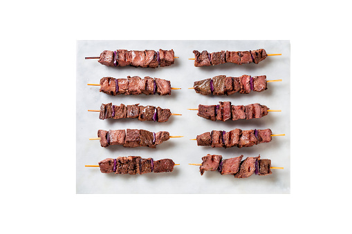 Grilled beef kebabs with red onion on the white plate