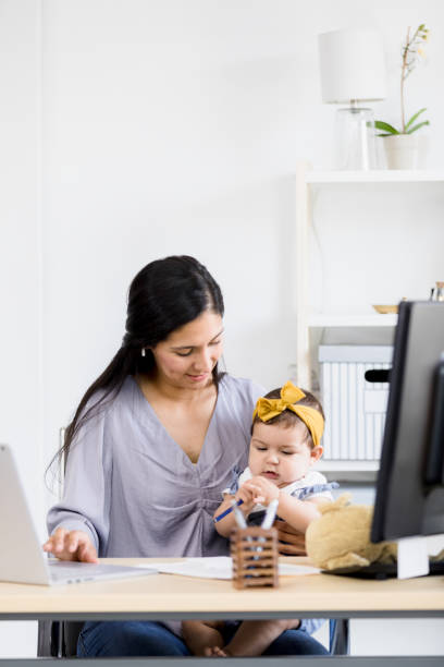 istock Work-from-home mom distracted by baby playing with pen 1396288956