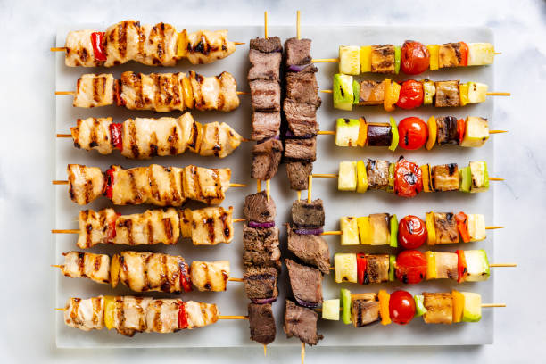 Grilled assorted kebabs (beef, salmon, shrimps, vegetarian) on the white plate stock photo