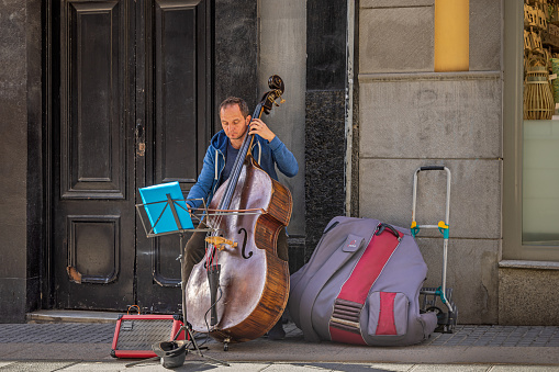 Street musician with a cello in a pedestrian street in the center of Santa Cruz which is the main city on the Spanish Canary Island Tenerife