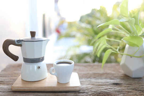 white cup and moka pot on wooden table