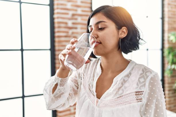 istock Young latin woman smiling confident drinking water at home 1396290548