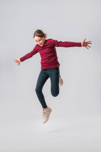 кавказская девочка-подросток прыгает в воздухе в студии - arms outstretched teenage girls jumping flying стоковые фото и изображения