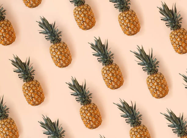 istock Bright pattern of many pineapples on a trendy soft beige pink background 1396293286
