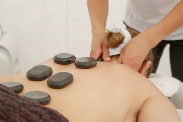 若い女性するホットストーンマッサージのスパサロン - massaging spa treatment stone massage therapist ストックフォトと画像