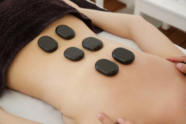 istock Young woman getting hot stone massage in spa salon 1396293450