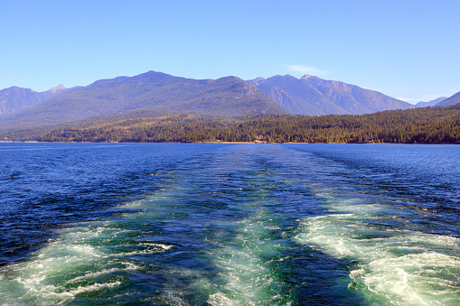 A ferry boat wake on Kootenay Lake with the Purcell Mountains in the background between Kootenay Bay and Balfour British Columbia, Canada.