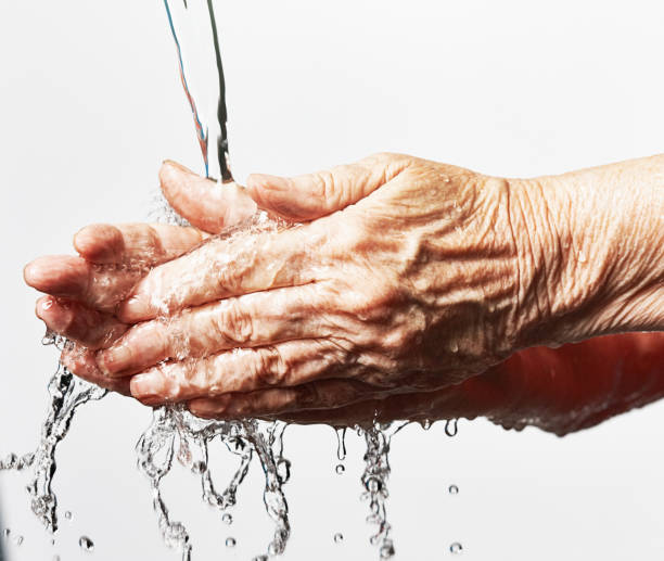 istock Water splashes as an elderly woman washes her hands hygienically 1396295773