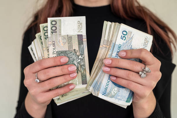 of several banknotes of 100 zlotys of Polish money held in the hands of a woman in a suit. close up of several banknotes denomination of 100 zlotys Polish money zlotys holding a fan in the form of a woman in a suit. The concept of zlotys in women's hands polish zloty stock pictures, royalty-free photos & images