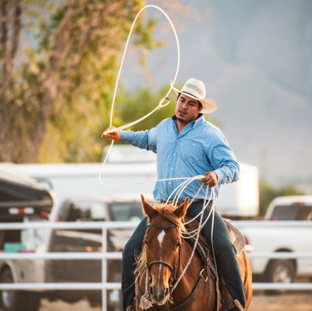 Front view of a cowbow swinging a lasso rope during a rodeo competition.